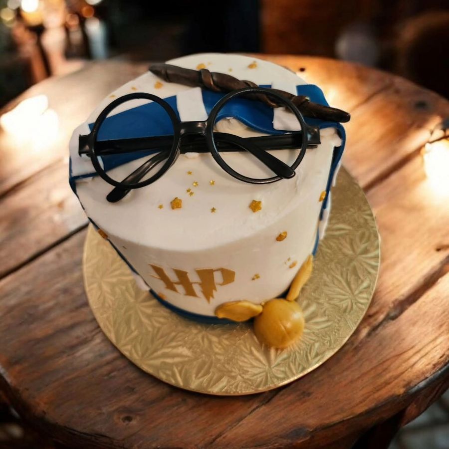 White Harry Potter cake with round glasses, a wand, scarf stripes and a golden snitch